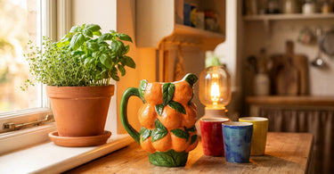 Appelsin kande i keramik fra &Klevering på køkkenbordet med krydderurter og kopper