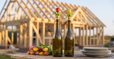Tulipan vinpropper i keramik fra &Klevering på vinflasker foran et nyt hus til rejsegilde