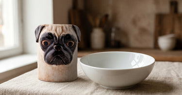 Mops-vase i stentøj fra Quail ved siden af en hvid porcelænsskål på hørdug