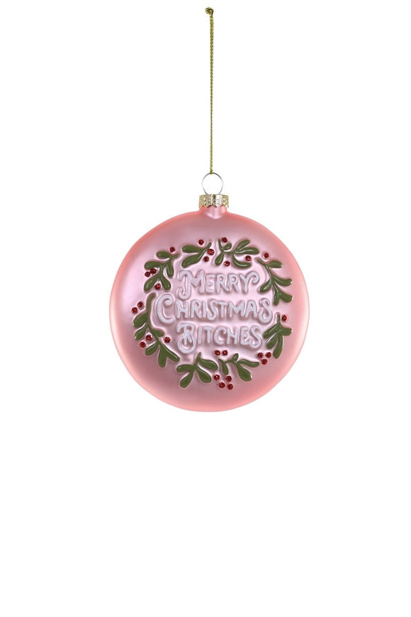 Lyserødt glasornament formet som julekrans med 'Merry Christmas' i guldskrift